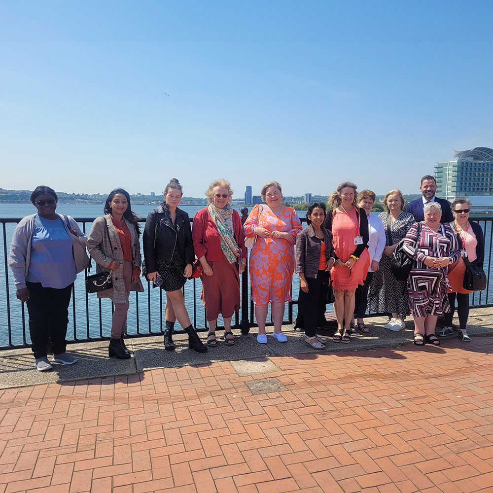 Caring team taking holiday standing on promenade overlooking water.
